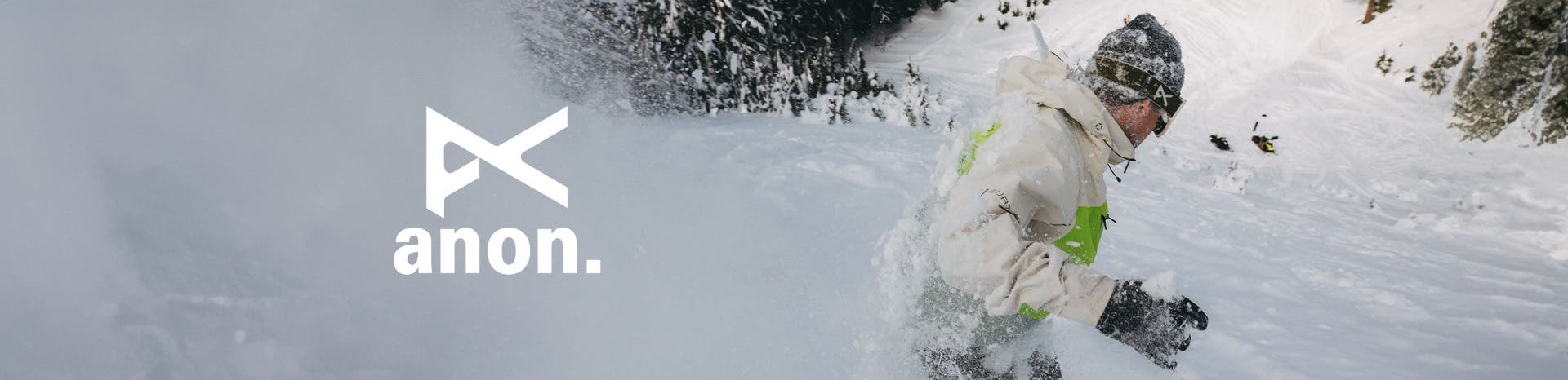 A white Anon logo and an image of a man wearing Anon goggles on his face while snowboarding down a mountain.