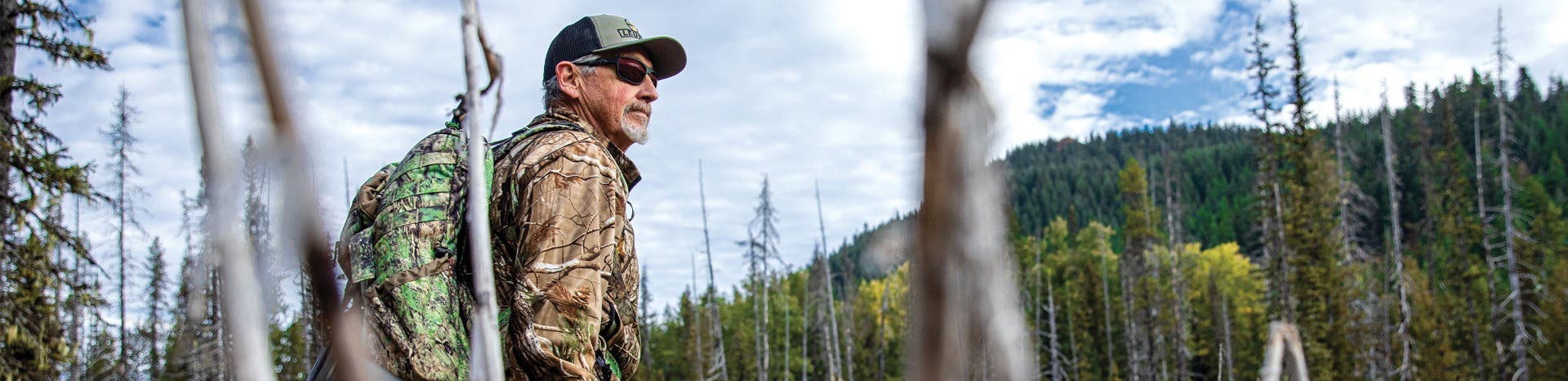 Image of man wearing hunting sunglasses on face while wearing camo in the woods.