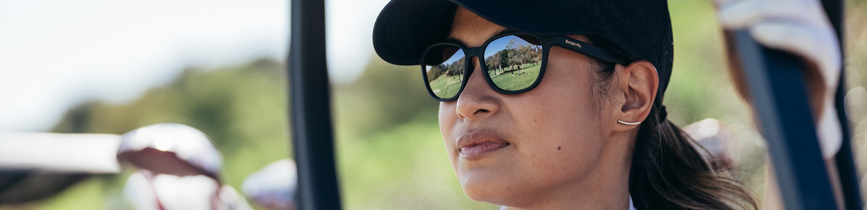 woman on a golf cart wearing SportRx women's golf sunglasses while viewing the golf course