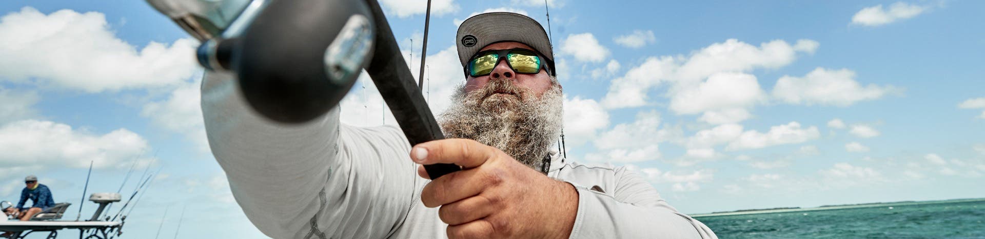 A bearded man wearing XL prescription sunglasses casts his reel in the open ocean.