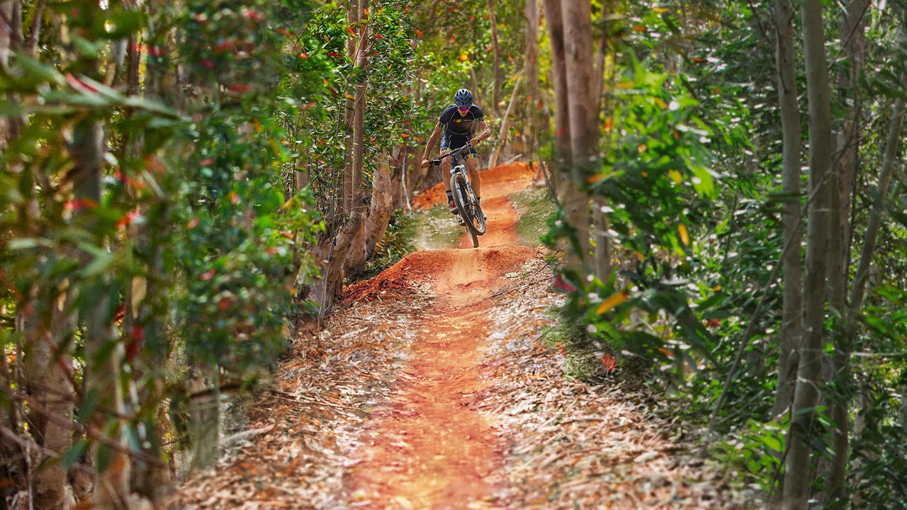 Man mountain biking on trail while wearing sunglasses.