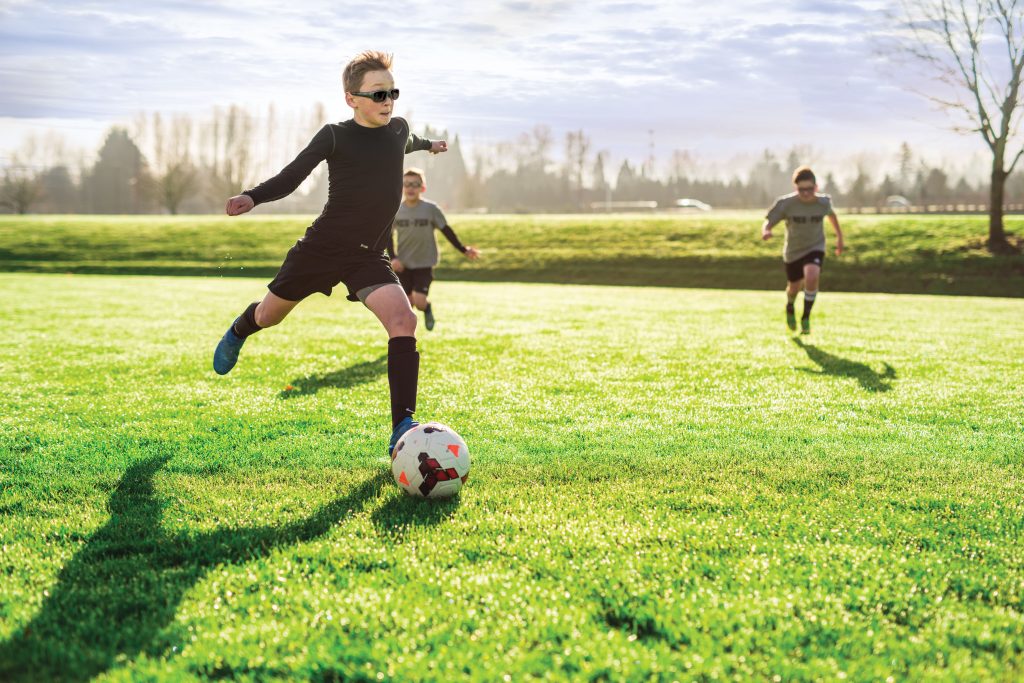 Child playing soccer while wearing protective sports glasses featuring the Wiley X Crush sunglasses.